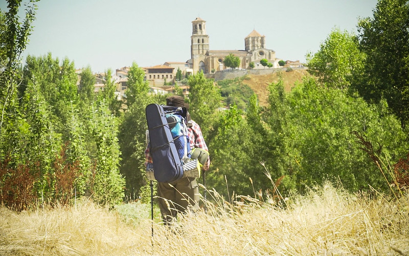 Alastair with rucksack and violin walking across a field