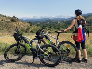Cyclist with two ebikes looking at mountain views over Limoux
