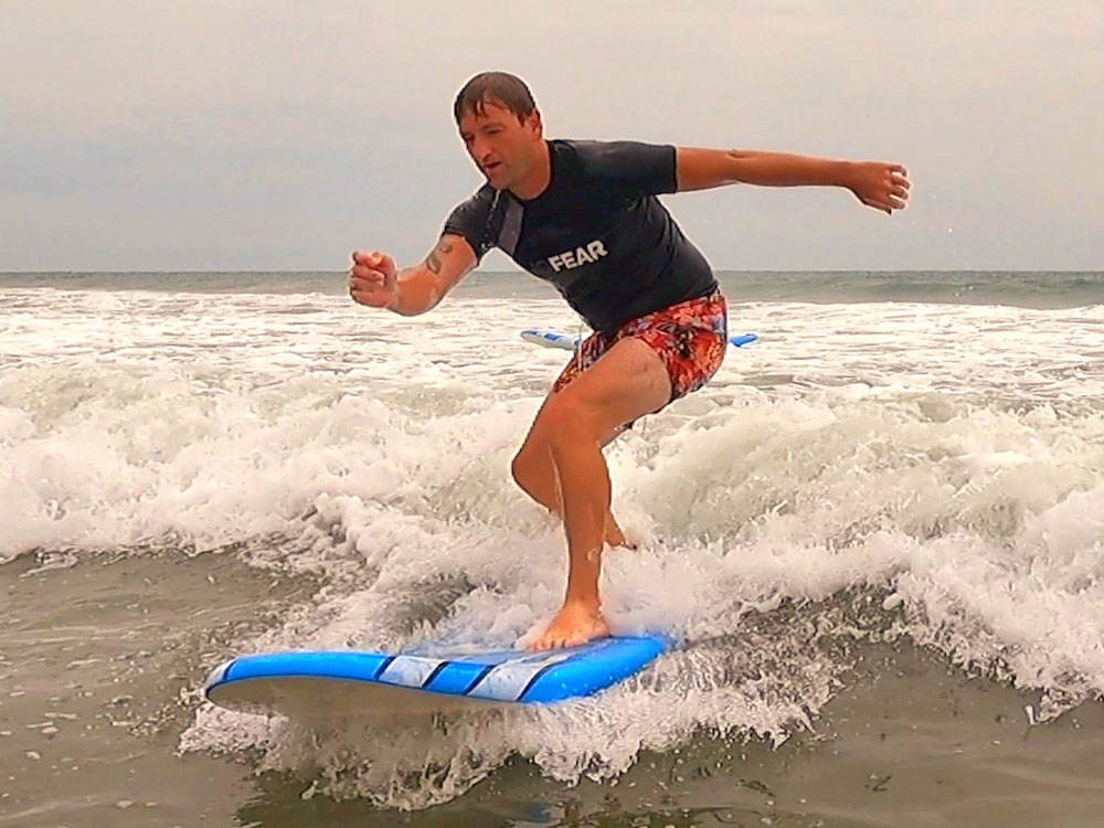 Patrick catching his first wave during Review of Free Spirit Hostel - copyright Cara Rees