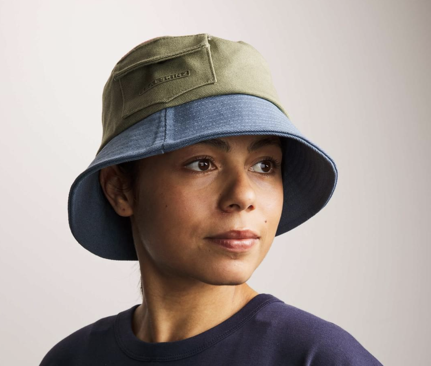 Female wearing a two-coloured fashionable adventure hat in blue and green
