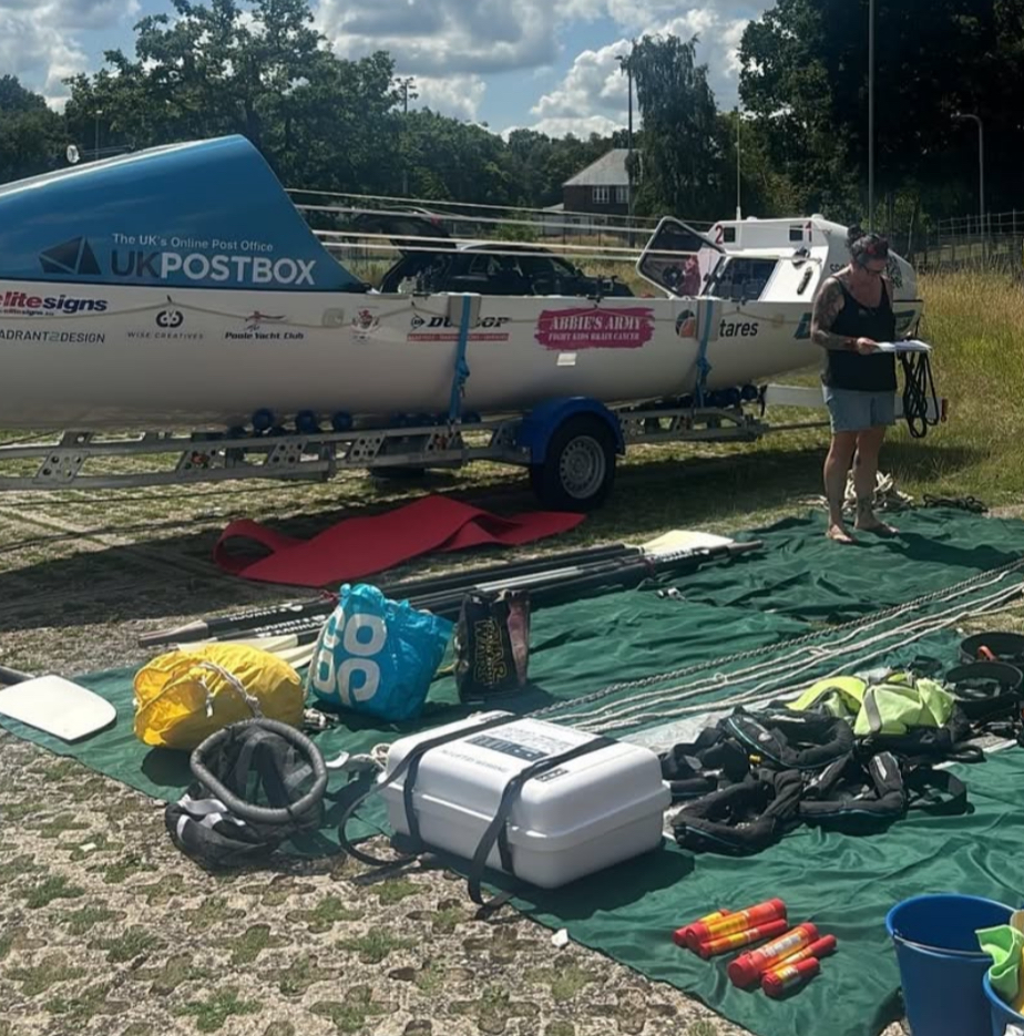 Equipment and stores layed out in front of a large atlantic rowing boat