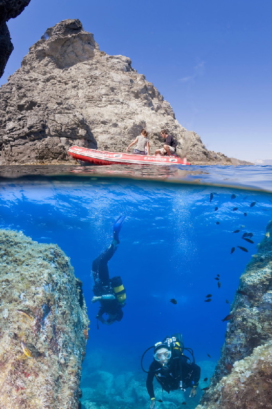 Two divers near rocks in clear water in France